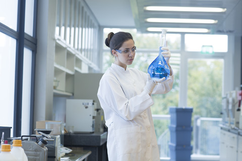 Junge Wissenschaftlerin mit Glaskolben in einem chemischen Labor, lizenzfreies Stockfoto