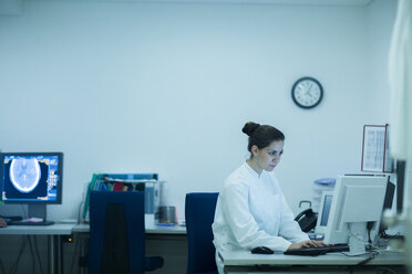 Young doctor in hospital looking at computer screen - SGF000912