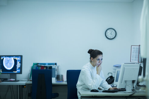 Young doctor in hospital looking at computer screen - SGF000913