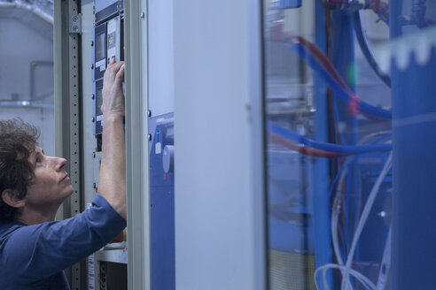 Female technical support specialist reducing the heat of a machine in a technical lab - SGF000919