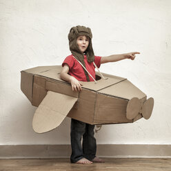 Kleiner Junge mit Pilotenhut und Pappkarton-Flugzeug zeigt auf etwas - MMFF000405