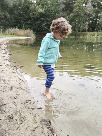 Junge watet im Wasser, lizenzfreies Stockfoto