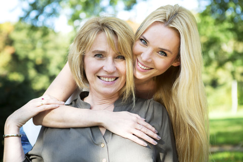 Portrait of smiling mother and adult daughter in park stock photo