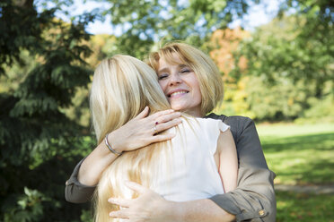 Mother and adult daughter embracing in park - GDF000533