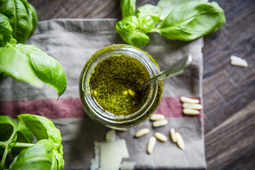 Ein Glas hausgemachtes Pesto Genovese, Pinienkerne, Basilikumblätter und Parmesan auf einem Küchenhandtuch - SARF000944