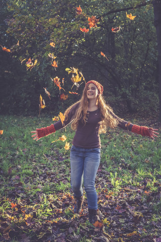 Teenager-Mädchen wirft Herbstblätter, lizenzfreies Stockfoto