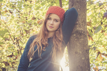 Portrait of teenage girl leaning at tree in autumn - SARF000953