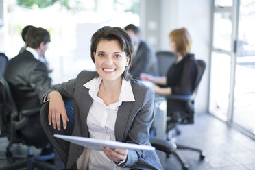 Lächelnde Geschäftsfrau mit Meeting im Hintergrund - ZEF002227