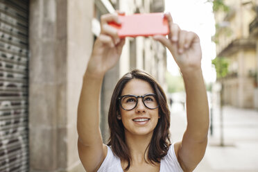 Porträt einer lächelnden jungen Frau, die ein Selfie mit ihrem Smartphone macht - EBSF000308