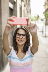 Porträt einer lächelnden jungen Frau, die ein Selfie mit ihrem Smartphone macht - EBSF000309
