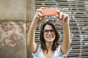 Porträt einer lächelnden jungen Frau, die ein Selfie mit ihrem Smartphone macht - EBSF000310