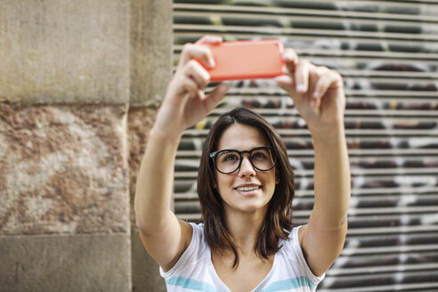 Porträt einer lächelnden jungen Frau, die ein Selfie mit ihrem Smartphone macht - EBSF000310