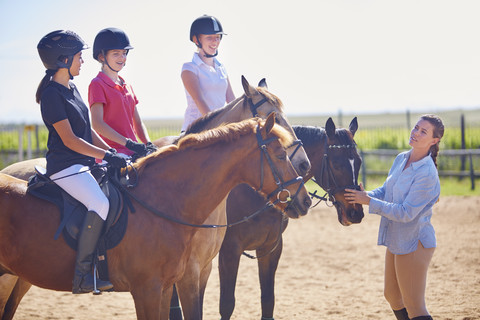 Trainer und Mädchen auf Pferden auf dem Reitplatz, lizenzfreies Stockfoto