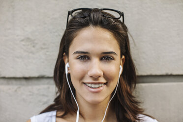 Portrait of smiling young woman with ear phones - EBSF000321