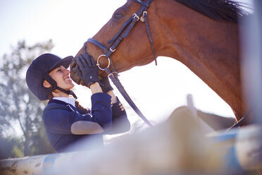 Smiling young woman with horse on show jumping course - ZEF001768