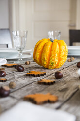 Yellow pumpkin, chestnuts and acorns on an autumnal laid table - LVF002097