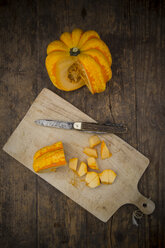 Sliced Chameleon pumpkin, chopping board and pocket knife on dark wood - LVF002149