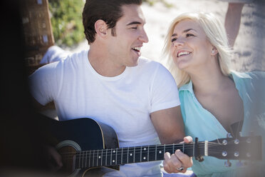 Junger Mann spielt Gitarre mit seiner Freundin am Strand - ZEF002442