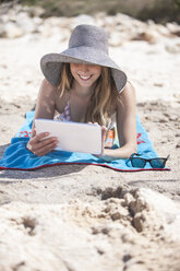 Lächelnde junge Frau mit digitalem Tablet am Strand - ZEF002458