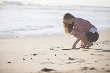 Junge Frau zeichnet Herz in Sand am Strand - ZEF002478