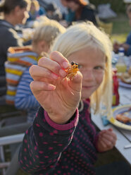Mädchen hält Krabben beim Grillen auf einem Campingplatz - LAF001180
