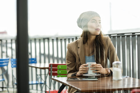 Daydreaming young woman sitting at sidewalk cafe - UUF002365