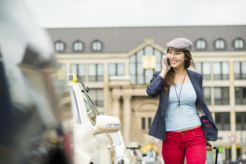 Young woman telephoning with smartphone walking along a street stock photo