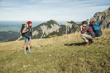 Austria, Tyrol, Tannheimer Tal, young man taking picture of girlfriend on alpine meadow - UUF002451