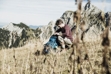 Österreich, Tirol, Tannheimer Tal, junger Mann mit Rucksack auf Almwiese - UUF002454