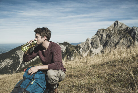 Österreich, Tirol, Tannheimer Tal, junger Mann mit Rucksack und Trinkflasche auf Almwiese - UUF002456