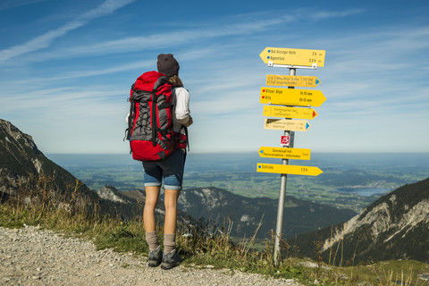 Österreich, Tirol, Tannheimer Tal, junge Frau auf Wanderschaft am Wegweiser, lizenzfreies Stockfoto