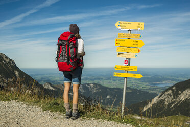 Österreich, Tirol, Tannheimer Tal, junge Frau auf Wanderschaft am Wegweiser - UUF002461