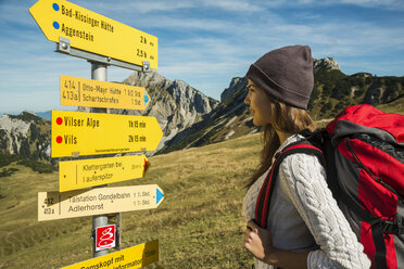 Österreich, Tirol, Tannheimer Tal, junge Frau auf Wanderschaft am Wegweiser - UUF002462