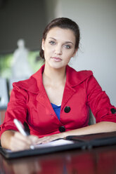 Portait of serious looking woman with red jacket in an office - ZEF001236