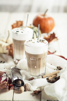 Zwei Gläser Kürbisgewürz-Latte Macchiato zwischen Gewürzen und herbstlicher Dekoration - SBDF001384