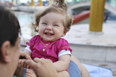 Portrait of laughing baby girl sitting on mother's lap - SHKF000090