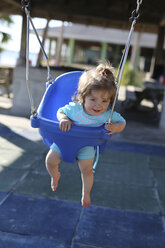 Lächelndes kleines Mädchen sitzt auf einer blauen Babyschaukel - SHKF000062