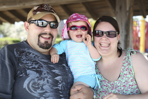 Vater, Mutter und ihre kleine Tochter mit Sonnenbrille, lizenzfreies Stockfoto