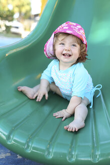 Lächelndes kleines Mädchen auf grüner Rutsche - SHKF000068