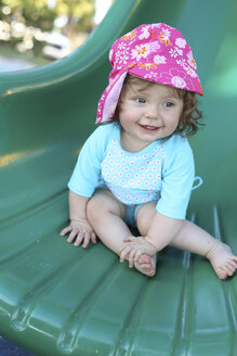 Lächelndes kleines Mädchen auf grüner Rutsche - SHKF000069