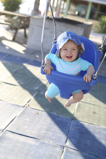 Lächelndes kleines Mädchen sitzt auf einer blauen Babyschaukel - SHKF000071