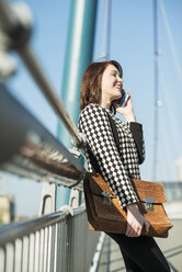 Deutschland, Frankfurt, junge Frau auf Brücke mit Mobiltelefon - UUF002474