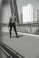 Deutschland, Frankfurt, junge Geschäftsfrau auf Brücke stehend mit Mobiltelefon - UUF002482
