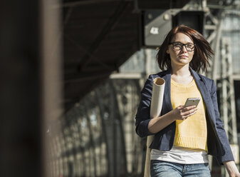 Junge Frau mit Mobiltelefon am Bahnhof - UUF002502