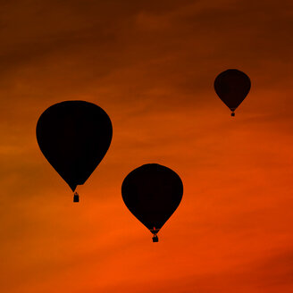 Silhouetten von drei Luftballons vor rotem Abendhimmel - HOHF001093
