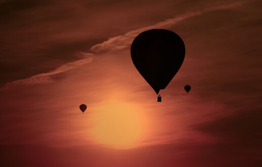 Silhouetten von drei Luftballons vor rotem Abendhimmel - HOHF001088