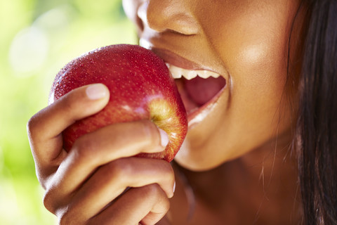 Frau beißt in roten Apfel, Nahaufnahme, lizenzfreies Stockfoto