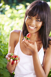 Portrait of smiling woman eating strawberries - ZEF001920