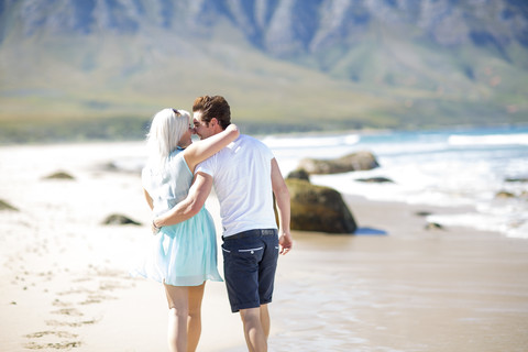 Glückliches junges Paar beim Spaziergang am Strand, lizenzfreies Stockfoto