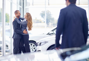 Couple hugging at car dealer - ZEF002019